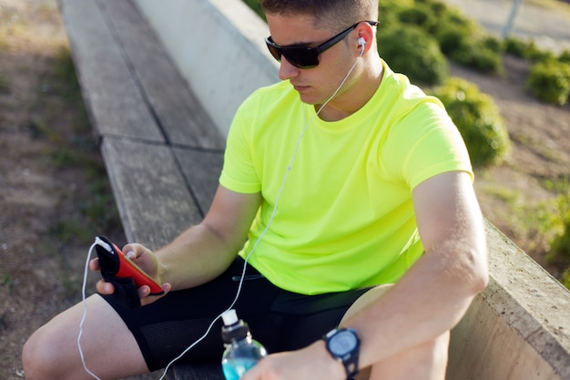 Sportsman on bench listening music