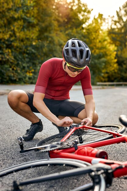 Sportsman bicycle cyclist repair parts and adjusting by himself on the road outdoors strong athlete ...