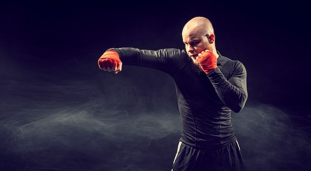Pugile sportivo combattendo su sfondo nero con boxe di fumo