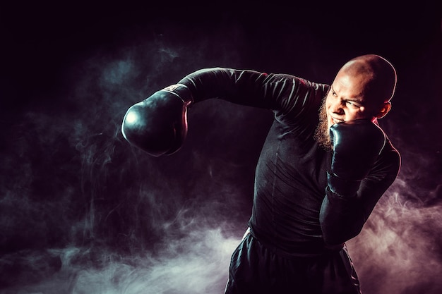 Sportsman boxer fighting, hitting side impact on black space with smoke