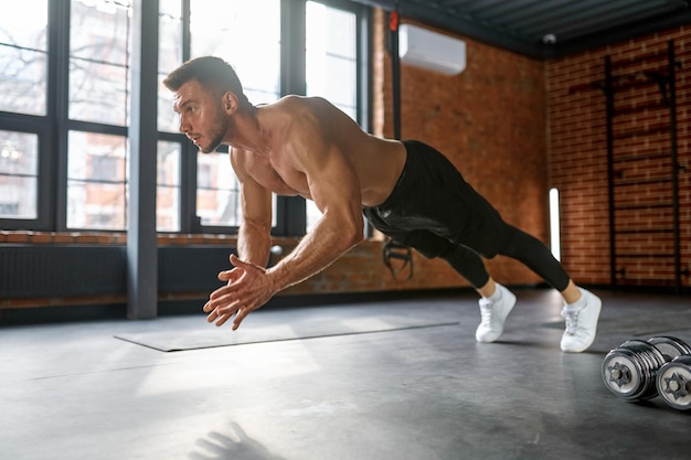 Sportivo che fa esercizio di flessioni con le mani in palestra. allenamento di forza esplosivo, allenamento fitness crossfit e concetto di forza