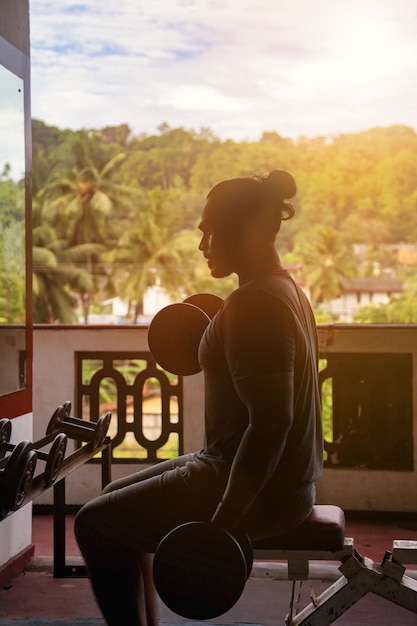 Photo sportsman doing exercises with dumbbells at old gym