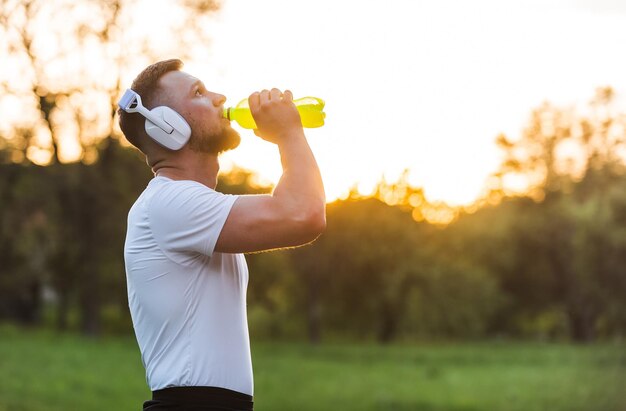 Sportsman drinking energy water from a bottle while resting after a run or workout Healthy lifestyle