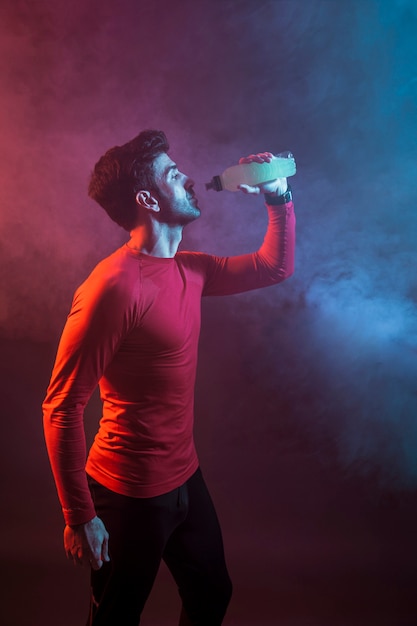 Foto sportivo che beve acqua di rinfresco in studio