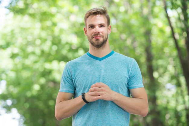 Sportsman inspiring confidence. Handsome sportsman or sports trainer on blurred natural background. Fit sportsman using fitness tracker during training outdoor. Confident sportsman or coach.