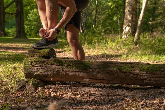 The sportsman is tying the laces of his legs in sneakers close up the athlete runs in the park