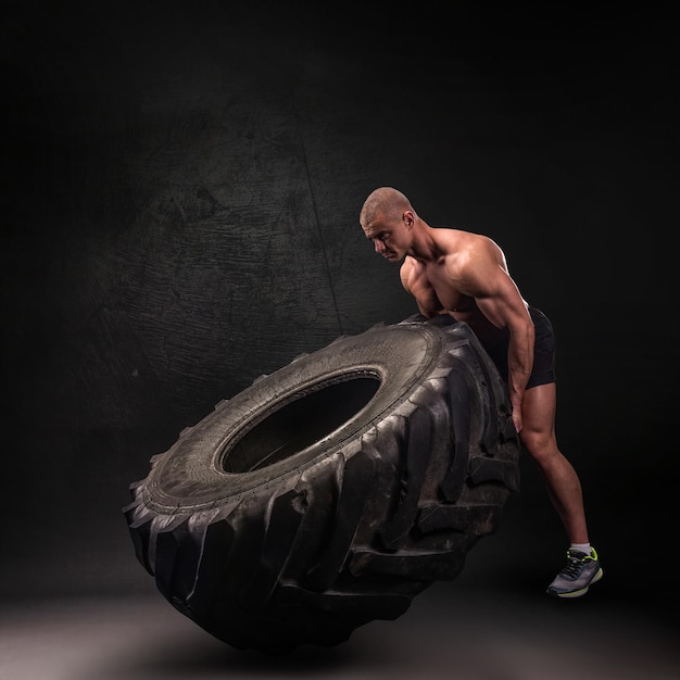 Sportsman lifting large heavy wheel in a gym