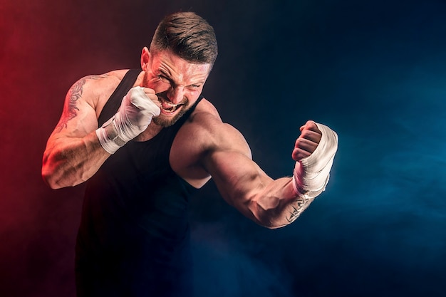 Sportivo muay thai boxer combattendo sul muro nero con fumo. concetto di sport.