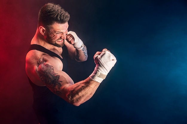 Sportsman muay thai boxer fighting on black wall with smoke. Sport concept.