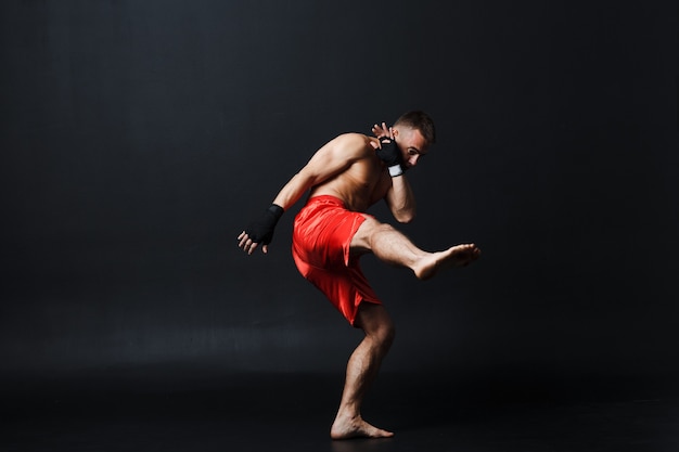 Sportsman muay thai man boxer stance at black background.