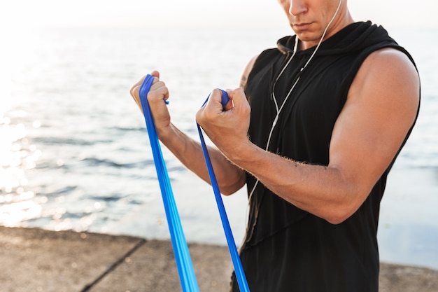 Foto lo sportivo all'aperto in spiaggia fa esercizi sportivi con attrezzature.