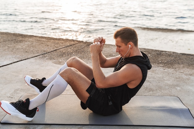 Спортсмен на открытом воздухе на пляже делает спортивные упражнения.