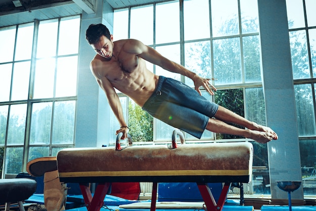 The sportsman performing difficult gymnastic exercise at gym The sport exercise gymnast