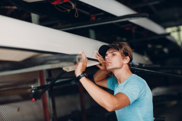 Sportsman single scull man rower prepare to competition with boat