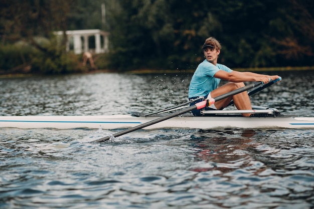 Sportsman single scull man rower rowing on boat