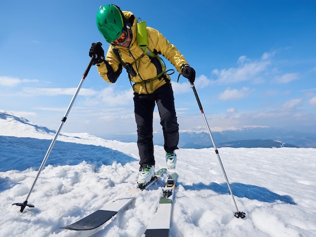 Sportsman skier on skis on snowy valley on background of bright blue sky and highland landscape