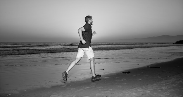 Velocista sportivo che corre sulla spiaggia estiva di alba alla sfida oceanica