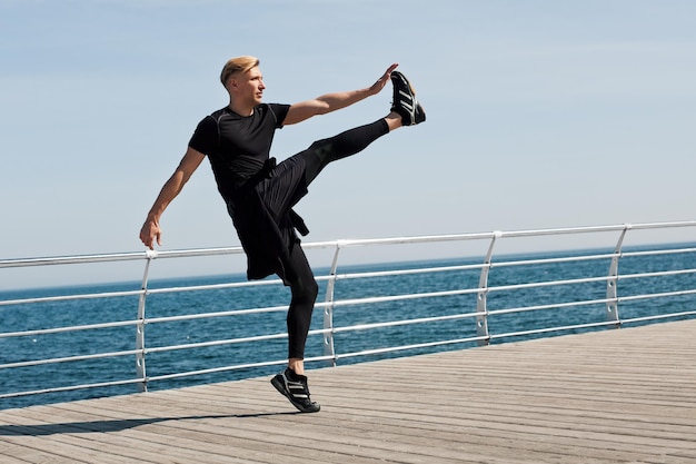 Photo sportsman stretching leg on seaside