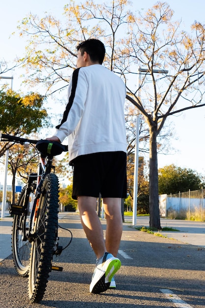 Foto sportivo che cammina con la sua bicicletta al mattino