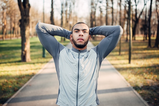 Sportsman warming up before run in autumn park