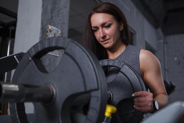 Sportiva che aggiunge pesi sulla pressa per gambe per il suo allenamento