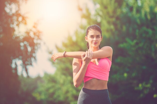 The sportswoman does exercise on the sunny background