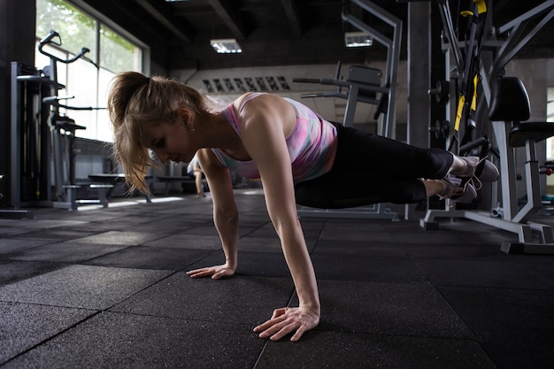 Sportswoman doing abs exercise with trx trainer at sport studio