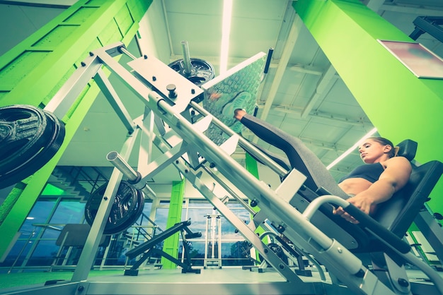 The sportswoman doing exercise for legs in the sport center