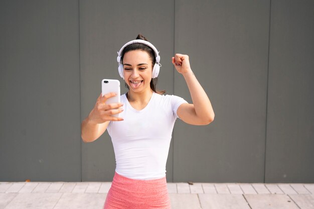 Sportswoman listening music on headphones out of the gym