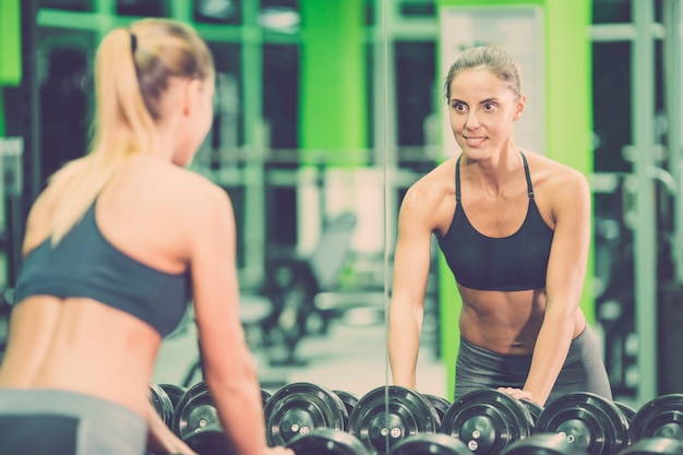 The sportswoman look in the mirror in the gym