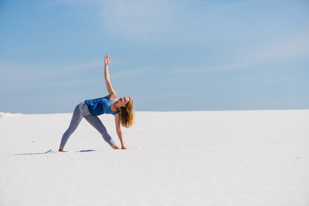 Sportswoman makes triangle yoga pose outdoors