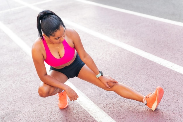 Sportswoman stretching legs on the athletics track