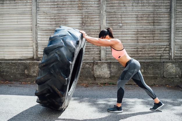 Photo sportswoman training outdoor weight lifting wheel