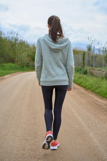 Sportiva che cammina lungo la strada di campagna