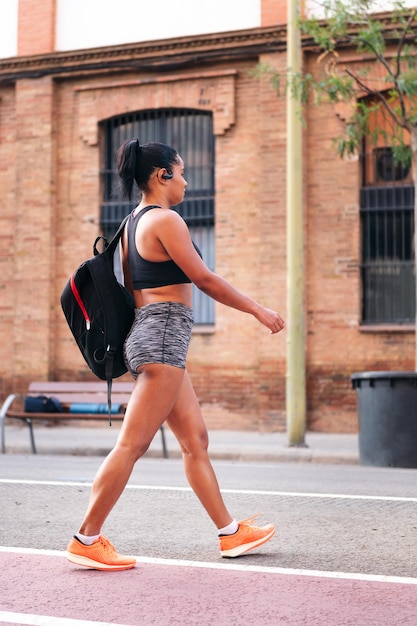 Sportswoman walking with a backpack in the city