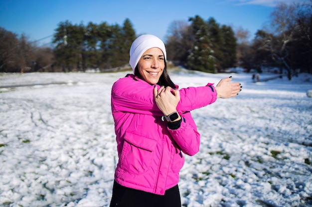 冬のスポーツウーマンは、雪のトレーニングの前に体を伸ばして体を温めます。