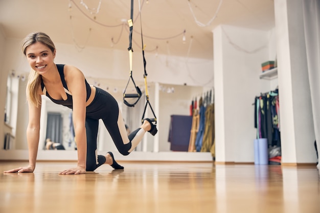 Sportswoman with her hands on the floor and the leg placed in the foot cradle looking ahead