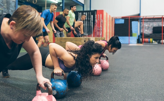 Sportswomen doing pushups with kettlebells