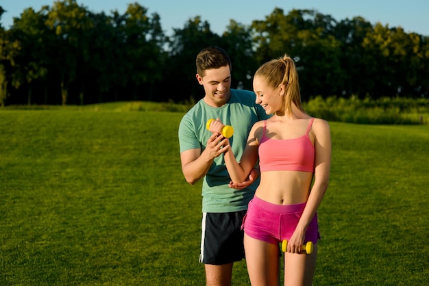 Sporttrainer die zich bezighoudt met sporten met een meisje in het park Sportactiviteiten in de natuur Fitness op straat Gezonde levensstijl