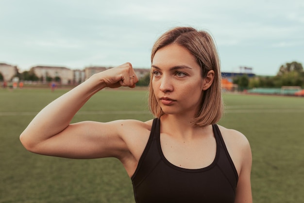 sportvrouw die biceps-spier laat zien terwijl ze op het sportveld in het stadion staat