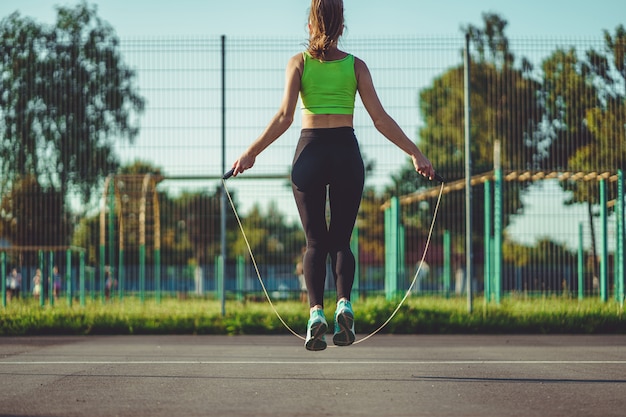 Foto sportvrouw doen cardio-oefeningen met touwtjespringen buitenshuis