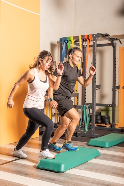 Sportvrouw en man doen stap-up sprongen in healthclub. Concept van oefeningen met apparatuur in de gezondheidsclub.