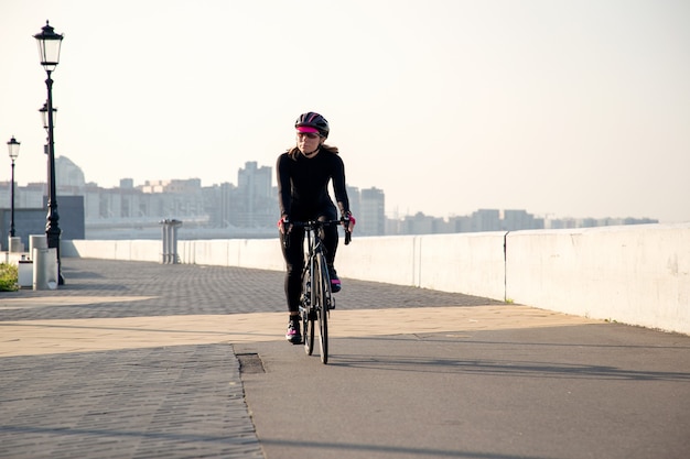 Sportvrouw fietser rijdt langs de dijk bij zonsopgang