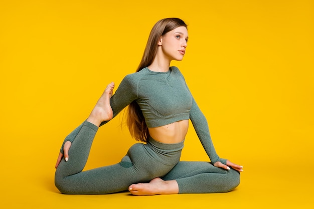 Sportvrouw in een groen pak voor fitness op een gele achtergrond