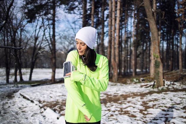 Sportvrouw in winterkleren lied kiezen voor training in het park tijdens het sneeuwt.