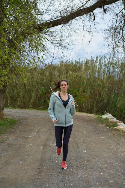 Sportvrouw met brunette vrouw in legging en sweatshirt die over het veld loopt, gezien vanaf de voorkant