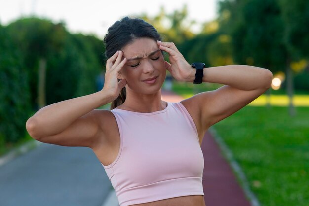 Foto sportvrouw met ernstige hoofdpijn met pijn en pijnlijke uitdrukking.