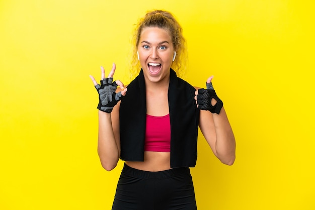 Sportvrouw met handdoek die op gele achtergrond wordt geïsoleerd die ok teken en duim omhoog gebaar toont
