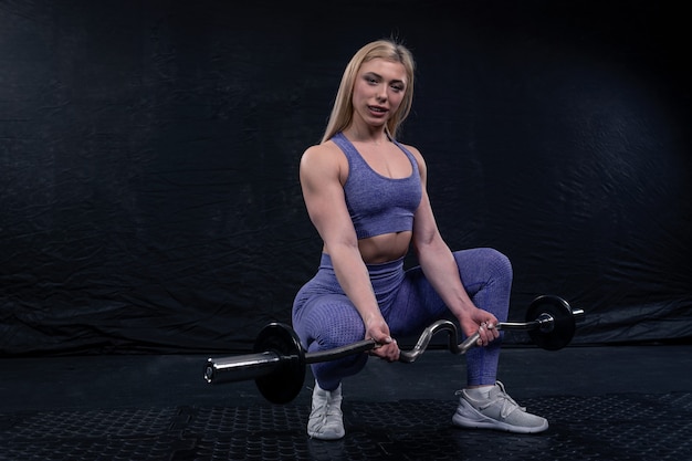 Sportvrouw poseren zittend met een barbell in haar handen