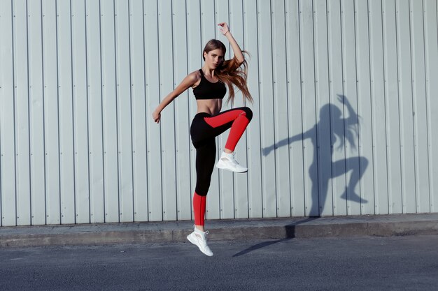 Sportvrouw springen en uitrekken. volledige lengte van gezonde vrouw die buiten traint en springt.